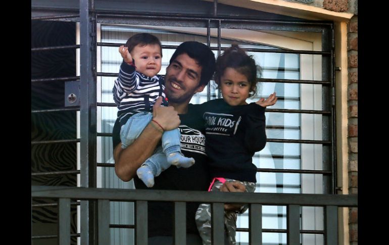 Luis Suárez sujeta a sus hijos Benjamín y Delfina desde una terraza ubicada en su casa de Lagomar, cerca de Montevideo. AFP /