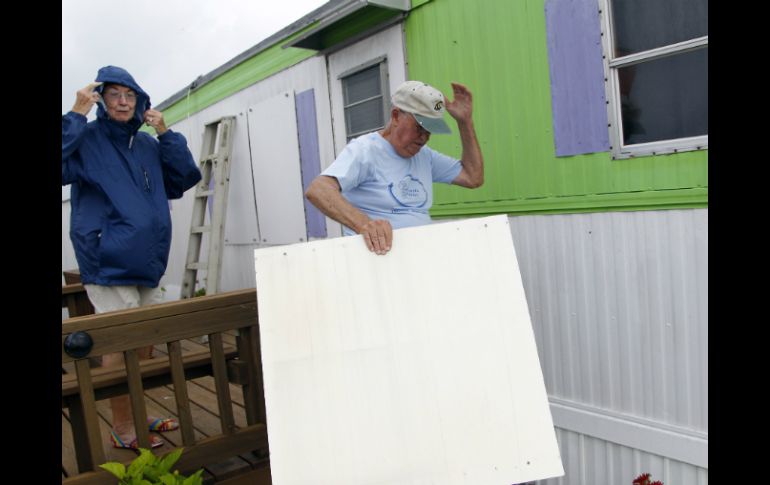 Dos ciudadanos resguardan su vivienda de los fuertes vientos originados por 'Arthur'. AP /