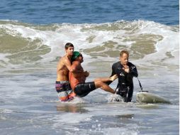 Dos hombres sacan del mar a Steven Robles tras ser atacado por un tiburón. AFP /