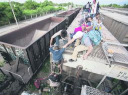 Abordan 'la bestia'. Adultos ilegales ayudan a un menor a abordar el tren de carga en Ixtepec, Oaxaca. AP /