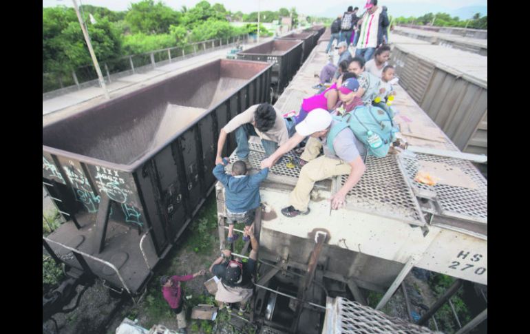 Abordan 'la bestia'. Adultos ilegales ayudan a un menor a abordar el tren de carga en Ixtepec, Oaxaca. AP /