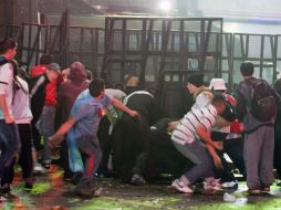 Fanáticos argentinos lanzan piedras a la policía, luego de la derrota de su Selección en el Mundial de futbol. AFP /