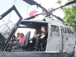 Una familia sube a un helicóptero de la Marina, expuesto en la plancha de la Plaza de la Liberación.  /