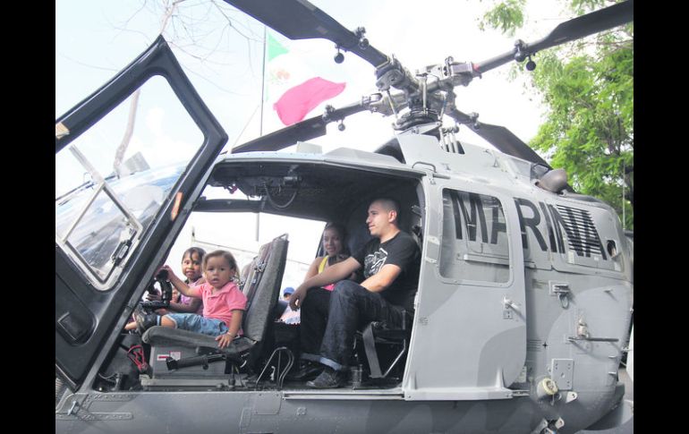 Una familia sube a un helicóptero de la Marina, expuesto en la plancha de la Plaza de la Liberación.  /