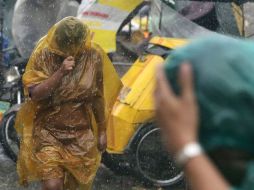 Residentes filipinos intentan protegerse del fuerte viento y lluvia por el paso del tifón ''Rammasun''. EFE /