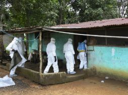 Enfermeros liberianos entran a una casa para trasladar el cuerpo de una víctima de ébola a un sitio para enterrarle. EFE /