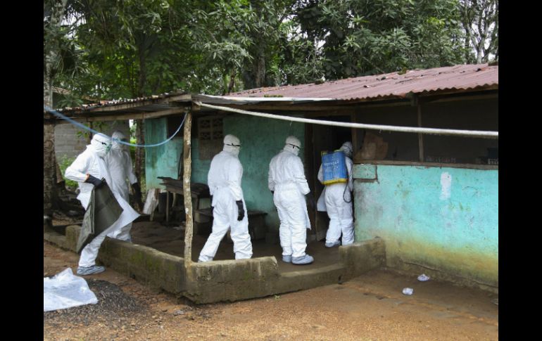 Enfermeros liberianos entran a una casa para trasladar el cuerpo de una víctima de ébola a un sitio para enterrarle. EFE /