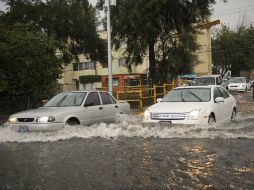 Dos automóviles atraviesan la inundación en Av. Patria.  /