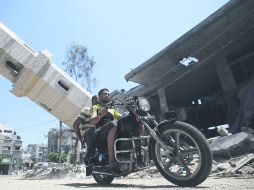 FRANJA DE GAZA . Dos palestinos pasan en motocicleta junto a un minarete de la mezquita Al-Sousi que se desplomó tras un ataque aéreo. EFE /