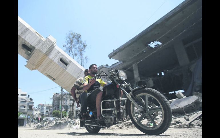 FRANJA DE GAZA . Dos palestinos pasan en motocicleta junto a un minarete de la mezquita Al-Sousi que se desplomó tras un ataque aéreo. EFE /