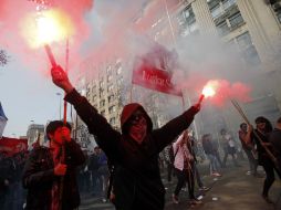 Un manifestante sostiene un par de bengalas. AP /