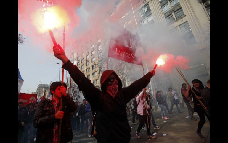 Un manifestante sostiene un par de bengalas. AP /