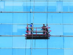 Con cuidado. Dos trabajadores limpian las ventanas del edificio de la Rectoría de la UdeG.  /