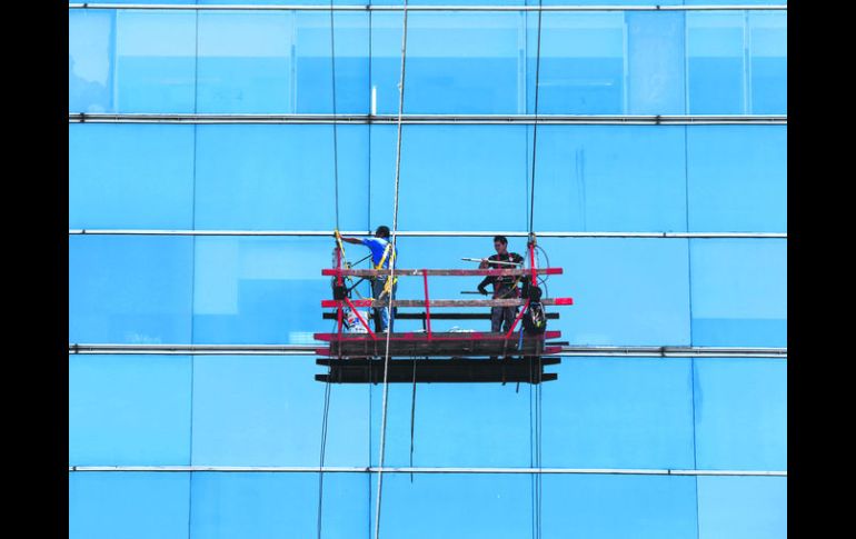 Con cuidado. Dos trabajadores limpian las ventanas del edificio de la Rectoría de la UdeG.  /