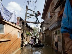 Un ciudadano lleva comida a unos vecinos que están atrapados en su casa en Srinagar. AP  Da Yasin  /