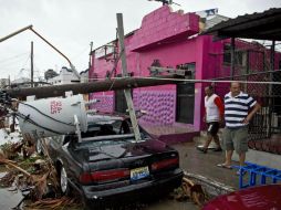 Un poste cae sobre un auto por los fuertes vientos y la intensa lluvia generada por 'Odile'. AFP  R. Schemidt  /