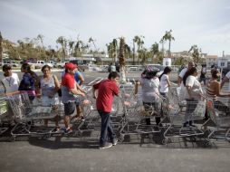 Personas hacen fila afuera de un supermercado que donó comida a los afectados por 'Odile'. AP  V. Caivano  /