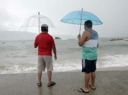 Dos personas observan, junto a una playa mexicana, el paso de ''Polo''. AFP P. Pardo  /