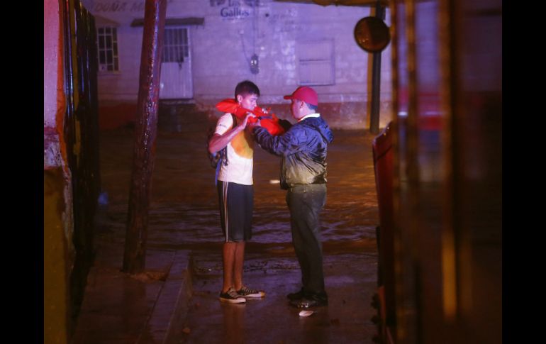 Vicente Sanz, jefe de Protección Civil, coloca un chaleco salvavidas a un hombre en Nogales. AP  M. Popat  /