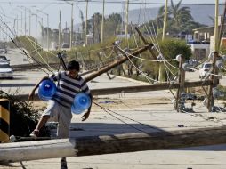 Un hombre camina entre postes derribados por los fuertes vientos generados por 'Odile'. EL UNIVERSAL  J. Serratos  /