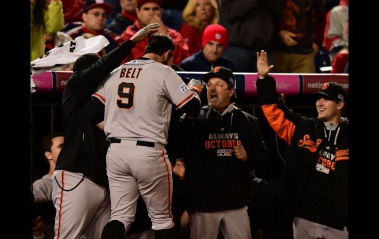 Brandon Belt es felicitado a la llegada a la caseta de los visitantes, luego de conectar su jonrón en la entrada 18. AFP / P. Smith