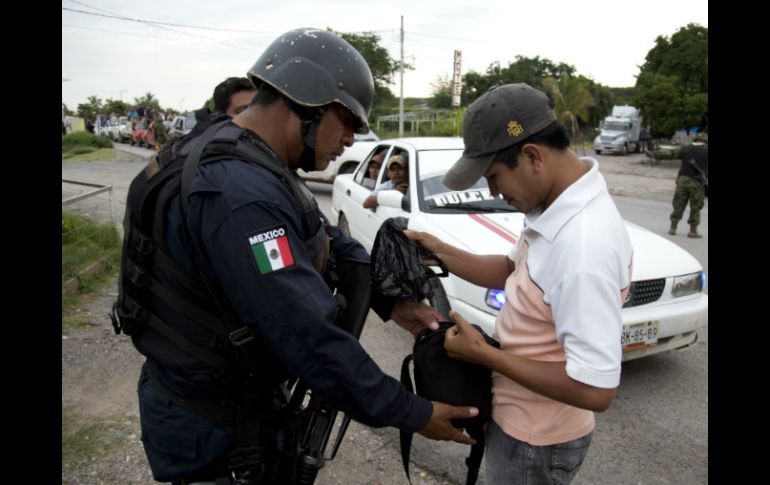 Un policía revisa a un miembro de la Policía Comunitaria cuando llega a colaborar en la búsqueda de los desaparecidos en Iguala. AP / E. Verdugo