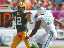 El mariscal de campo de los Empacadores,  Aaron Rodgers (12), trata de mantener a raya al defensa  de los Delfines, Cameron Wake (91). AFP / M. Ehrmann