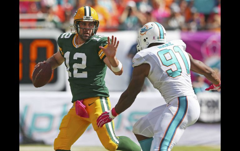 El mariscal de campo de los Empacadores,  Aaron Rodgers (12), trata de mantener a raya al defensa  de los Delfines, Cameron Wake (91). AFP / M. Ehrmann