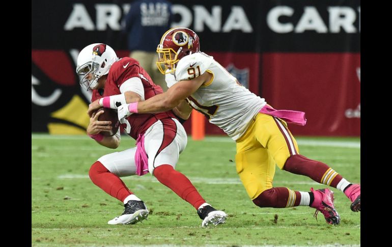 El mariscal de campo de los Cardenales, Carson Palmer es atacado por el apoyador de los Pieles Rojas,  Ryan Kerrigan. AFP / N. Hall