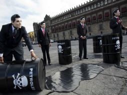 Con tambos vacíos y bolsas de plástico simulan tirar petróleo. AP / R. Blackwell