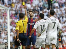 El árbitro Gil Manzano (i) saca la tarjeta amarilla al defensa del FC Barcelona Gerard Piqué (c). EFE / J. Hidalgo