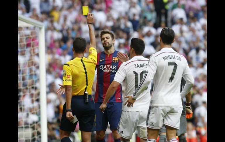 El árbitro Gil Manzano (i) saca la tarjeta amarilla al defensa del FC Barcelona Gerard Piqué (c). EFE / J. Hidalgo