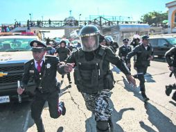 Agresiones. Oficiales de la Policía corren al ser atacados por comerciantes informales, quienes los persiguen con palos y piedras. EL INFORMADOR / F. Atilano