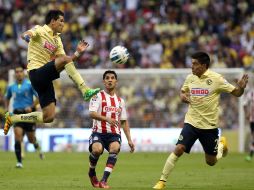 Los jugadores del América, Jesús Molina (i) y Paolo Goltz (d), disputan el balón con Ángel Reyna (c) de Chivas durante el Clásico. EFE / A. Cruz