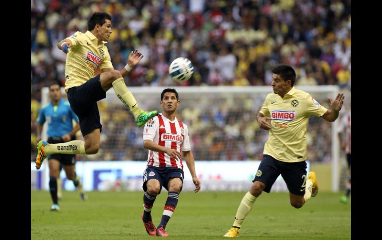 Los jugadores del América, Jesús Molina (i) y Paolo Goltz (d), disputan el balón con Ángel Reyna (c) de Chivas durante el Clásico. EFE / A. Cruz