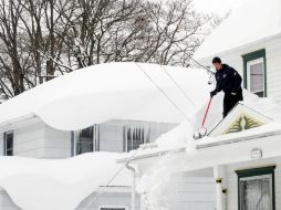 Personas trepan a los techos de las casas para palear la nieve y reducir el peligro de desplome. AP / G. Wiepert