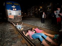 Un grupo se acuesta en las vías del tren, forzando a que este detenga su camino. AP / N. Berger