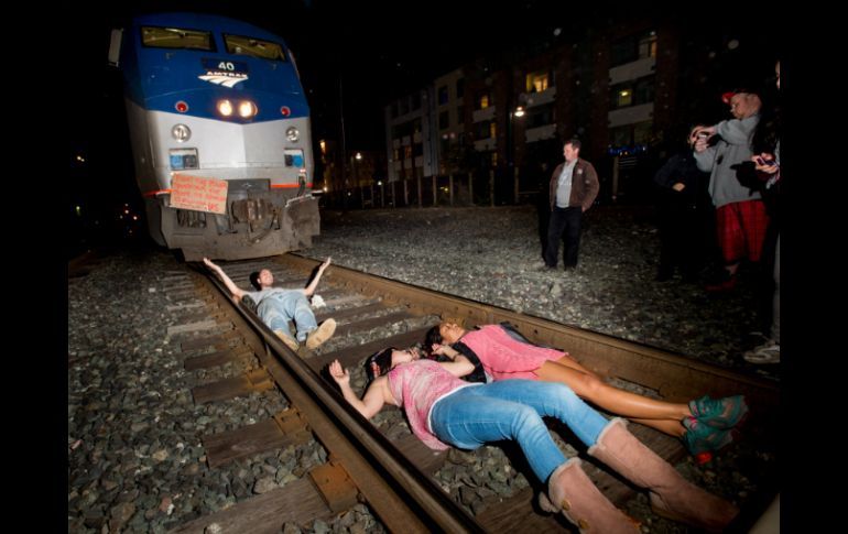 Un grupo se acuesta en las vías del tren, forzando a que este detenga su camino. AP / N. Berger