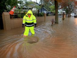 Un trabajador público destapa una alcantarilla para contrarrestar los efectos de la inundación en una calle de California. AP /