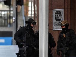 Policías armados vigilan a las afueras de la cafetería donde permanecen los rehenes. AFP /