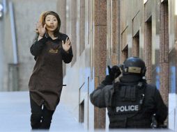 Una empleada abandona la cafetería donde trabaja y que un hombre armado tomó en Sídney. EFE / J. Carrett