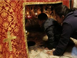 Dos peregrinos observan dentro de una gruta el lugar en el que se cree nació Jesús. AFP / A. Gharabli