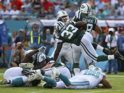 El corredor Chris Ivory (33) de los Jets de Nueva York, salta por encima de la defensa de los Delfines de Miami. AFP / M. Ehrmann