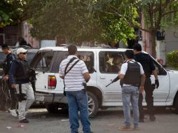 Agentes estatales resguardan un vehículo baleado en la zona donde se registró un enfrentamiento entre civiles y federales. EFE / L. Granados