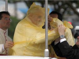 Asistentes del Papa le colocan un impermeable, ante la fuerte lluvia en el aeropuerto de Tacloban, donde ofició una misa. EFE /