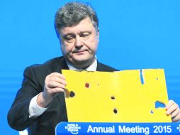 Poroshenko, muestra la placa perforada por balas durante su intervención en la sesión inaugural del Foro Económico Mundial de Davos. EFE /