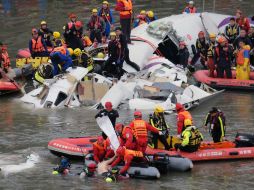 Los rescatistas extraen también piezas de equipaje de una puerta abierta del avión para despejar el fuselaje. AFP / S. Yeh