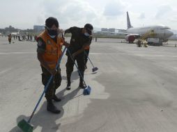 Trabajan en la limpieza de los restos de ceniza en la pista para poder habilitar el aeropuerto La Aurora. AFP / J. Ordonez