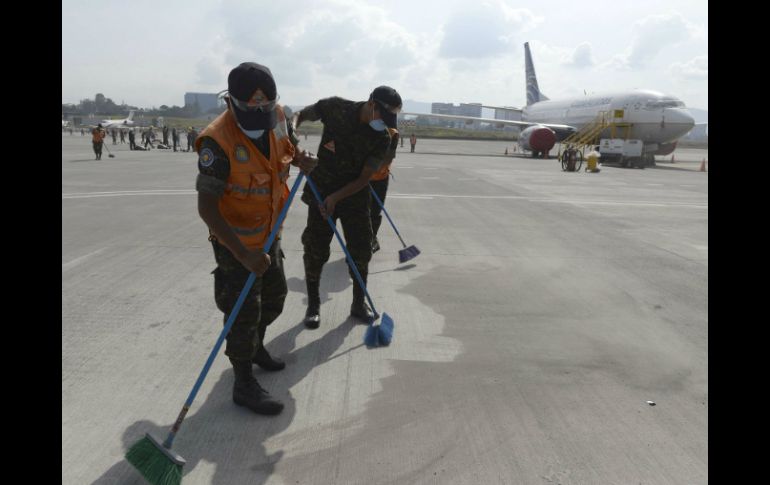 Trabajan en la limpieza de los restos de ceniza en la pista para poder habilitar el aeropuerto La Aurora. AFP / J. Ordonez