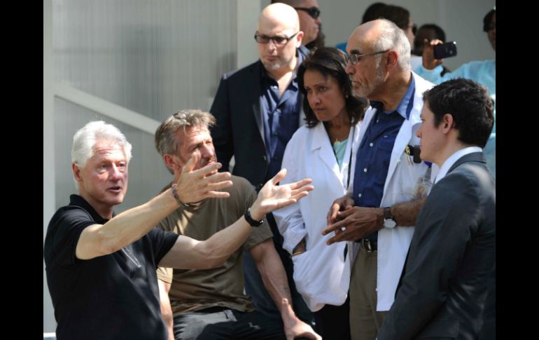 Clinton y Penn platicando con el equipo de un centro en construcción para el tratamiento del cólera. AFP / H. Retamal